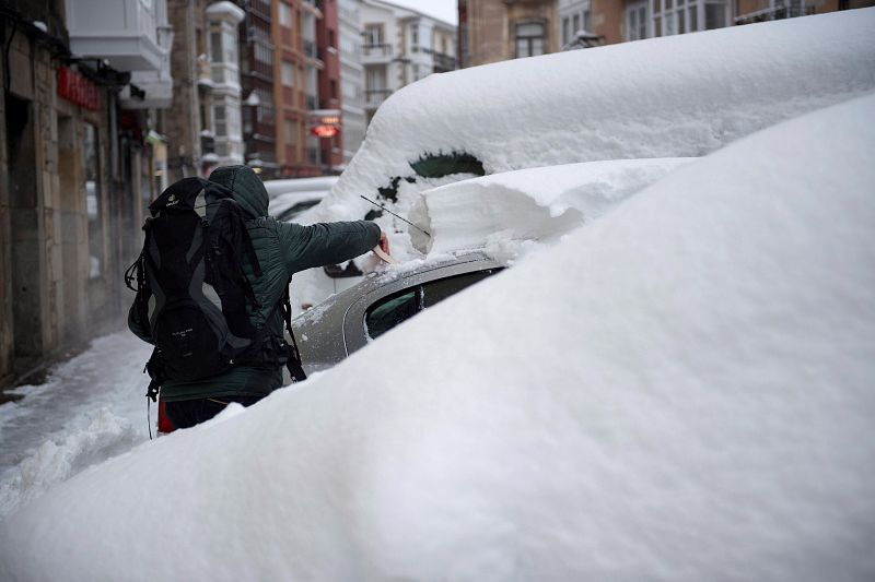 Un hombre quita la nieve de un coche en la localidad cántabra de Reinosa