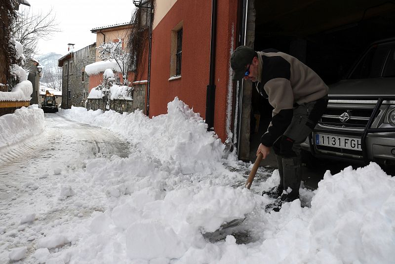 Un hombre quita la nieve acumulada junto a su casa en la localidad de Puebla de Lillo