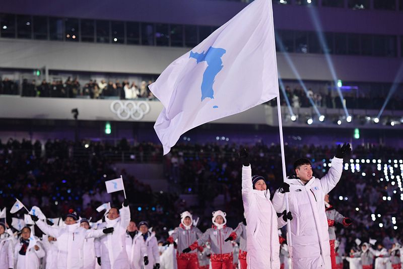 La jugadora de hockey de Corea del Norte Hwang Chung Gum y Won Yun-jong, piloto de bosleigh de Corea del Sur, portan la bandera unificada de Corea en el desfile de la ceremonia de inauguración de los Juegos de Pyeongchang 2018.
