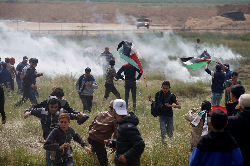 Varios palestinos huyen de los gases lacrimógenos lanzados por las tropas isrealíes