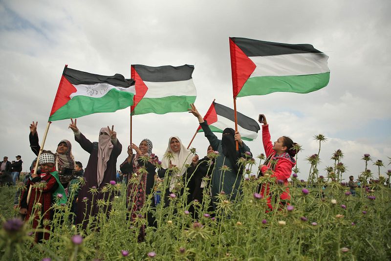 Mujeres palestinas sostienen banderasa palestinas durante las protestas en la frontera entre Gaza e Israel.