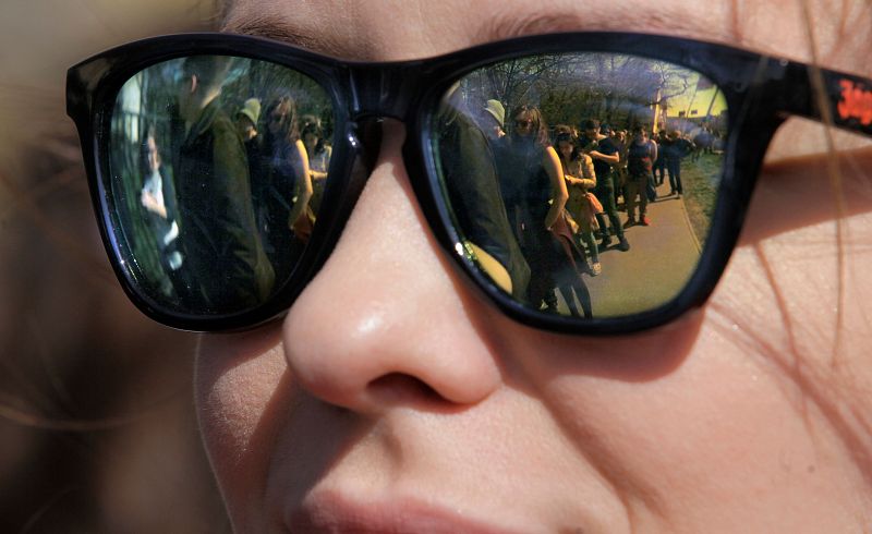 Una fila de votantes se refleja en las gafas de sol de una mujer que espera en un colegio electoral en Budapest