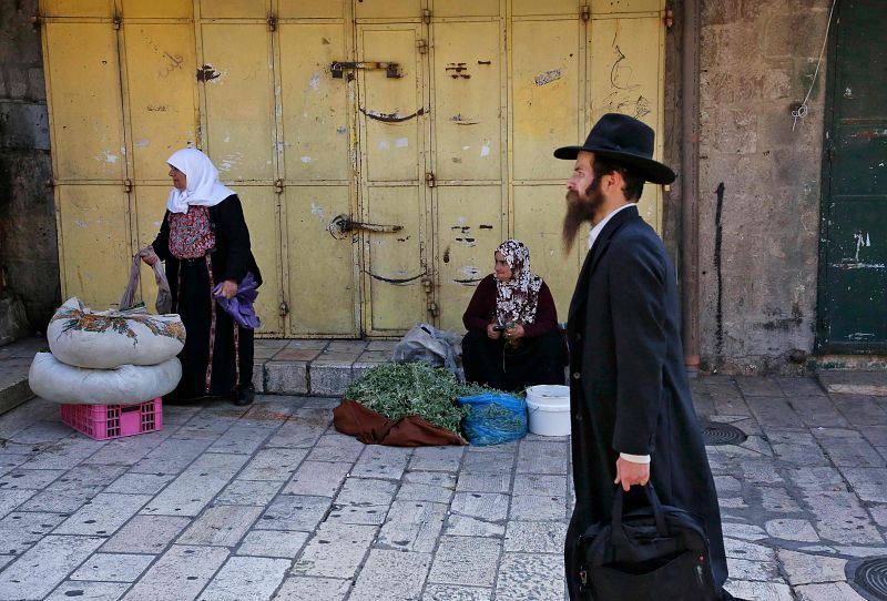 Un judío ultraortodoxo pasea entre vendedoras palestinas de verduras en la Ciudad Vieja de Jerusalén