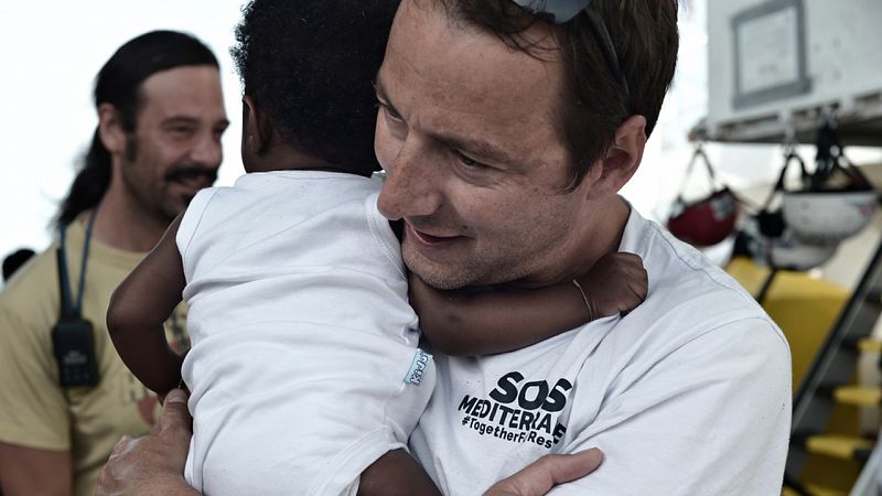 Un cooperante del Aquarius sostiene a un bebé refugiado