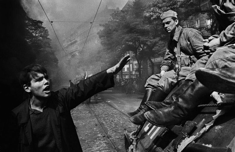 Un joven, con un gesto que parece decir 'parad', llama la atención de los soldados soviéticos apostados sobre un tanque