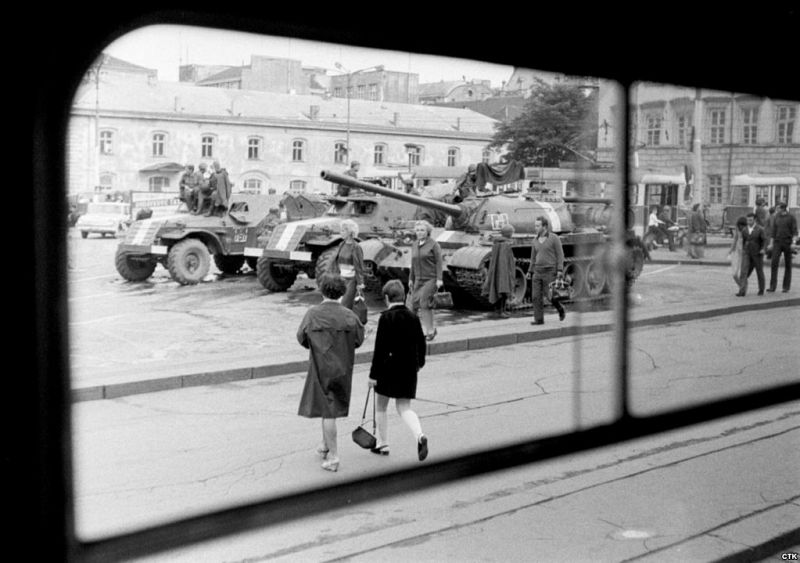 Varios ciudadanos cruzan entre los tanques y vehículos blindados soviéticos que siguen vigilantes en la Plaza de la República de Praga.
