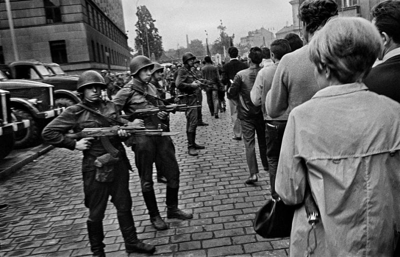 Una columna de soldados del Pacto de Varsovia se mantienen en guardia mientras pasa un grupo de ciudadanos de Praga