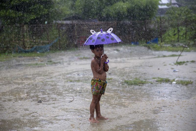 Un niño rohinyá se refugia de la lluvia en Rakáin