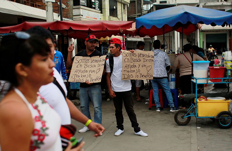 Migrantes venezolanos en Tumbes, Perú, con carteles en los que solicitan ayuda y trabajo