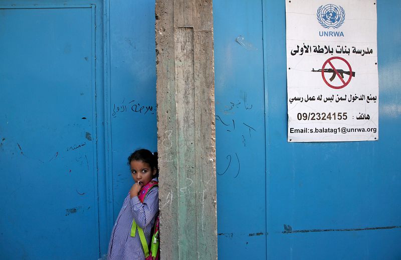 Una niña espera frente a la pared de la escuela