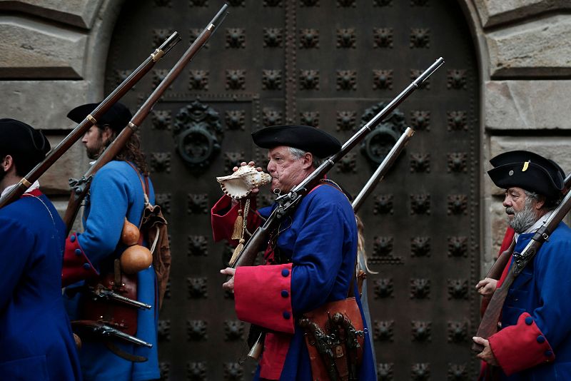 Un hombre uniformado de 'Miquelets de Catalunya' sopla una concha marina