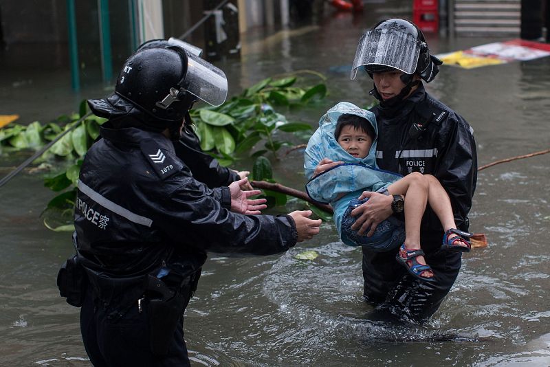 La Policía rescata a un niño en una calle inundada en Lei Yu Mun, Hong Kong. EFE/EPA/JEROME FAVRE