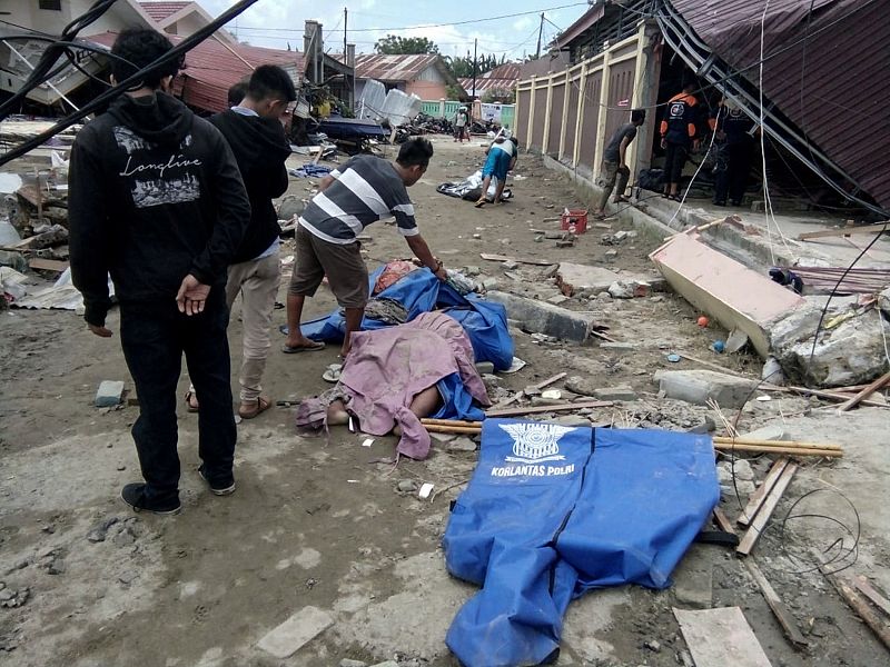 Varias personas buscan a sus familiares entre los muertos en una calle de Palu
