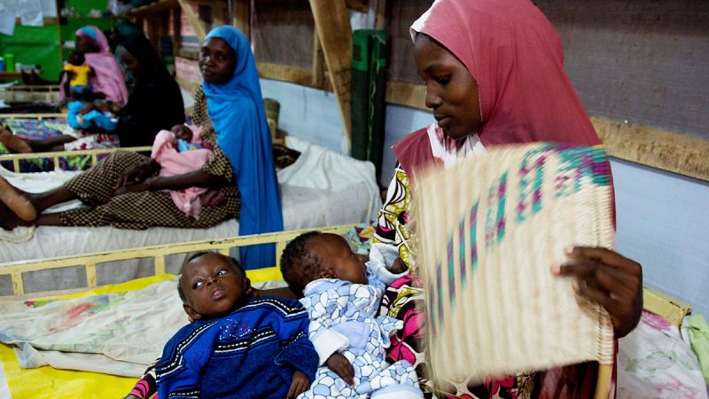 Una madre abanica a sus dos hijos gemelos ingresados por desnutrición en el Hospital de Zinder (Níger).