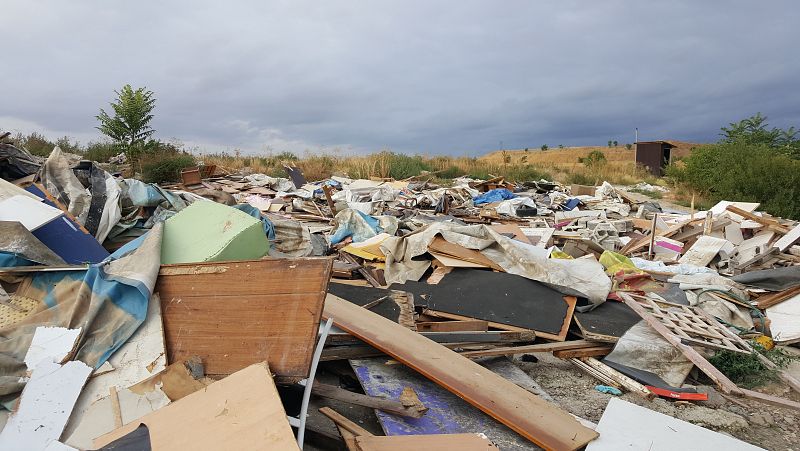Escombros. Al fondo una letrina en pie
