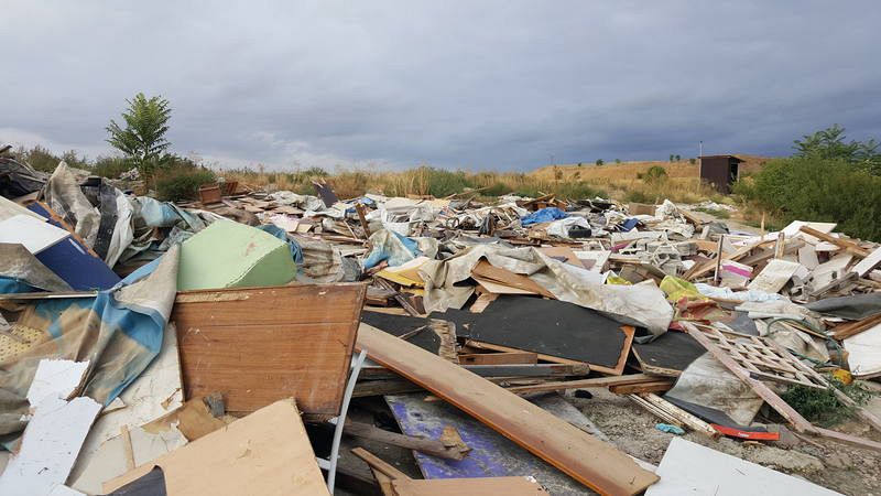 Escombros. Al fondo una letrina en pie