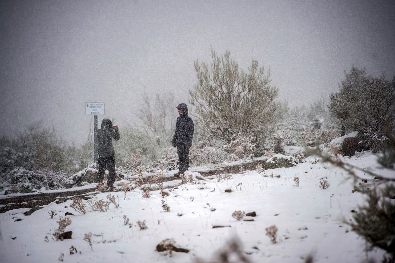Dos personas se hacen fotografias en la carretera de acceso a la localidad cántabra de Brañavieja