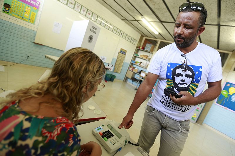 Un hombre con una camiseta en apoyo a Bolsonaro vota en un colegio electoral en la ciudad de Brasilia