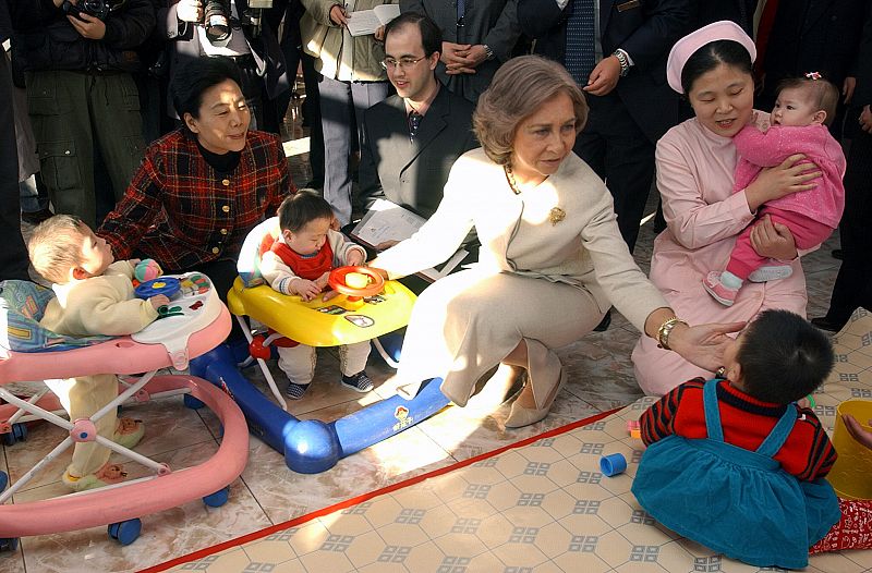 La reina Sofía con unos niños durante la visita al Instituto de Beneficiencia Infantil de Pekín
