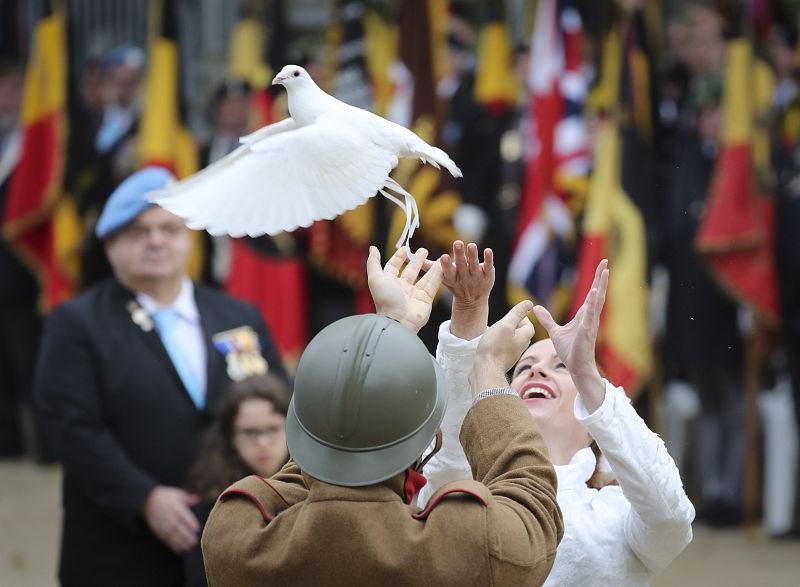 Dos personas lanzan una paloma durante una ceremonia en la tumba del soldado desconocido en la Columna de Congres, en Bruselas, Bélgica