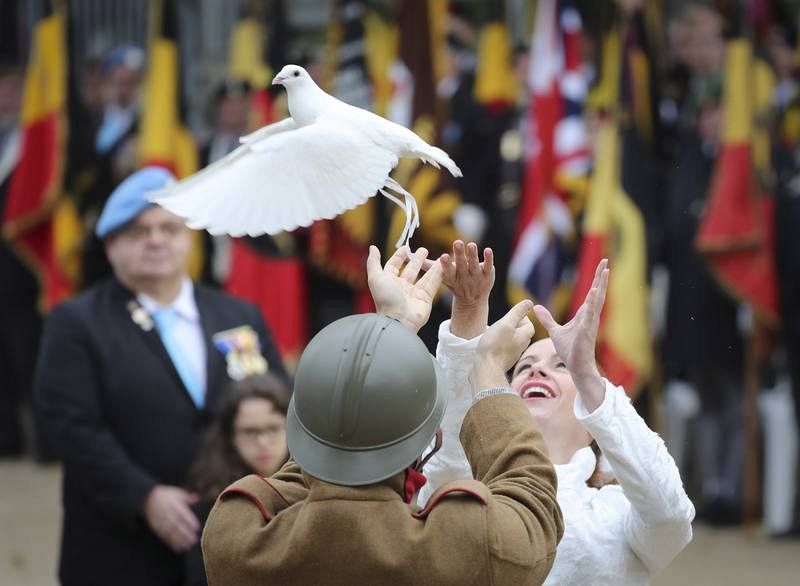 Dos personas lanzan una paloma durante una ceremonia en la tumba del soldado desconocido en la Columna de Congres, en Bruselas, Bélgica