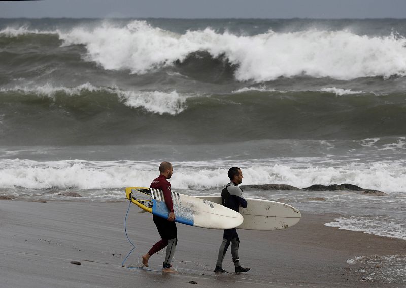 Dos surfistas aprovechan el fuerte oleaje en la playa de la Barceloneta durante el temporal marítimo que afecta a toda la costa catalana