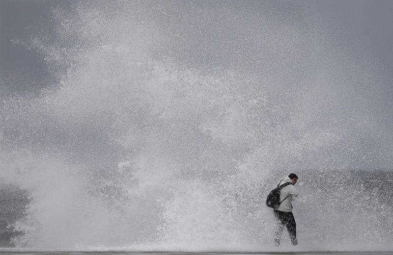 Un ciudadano desafía el fuerte oleaje en la playa de la Barceloneta, durante el temporal marítimo que afecta a toda la costa catalana