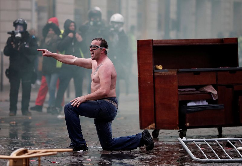 Un hombre se arrodilla desafiante frente a la policía