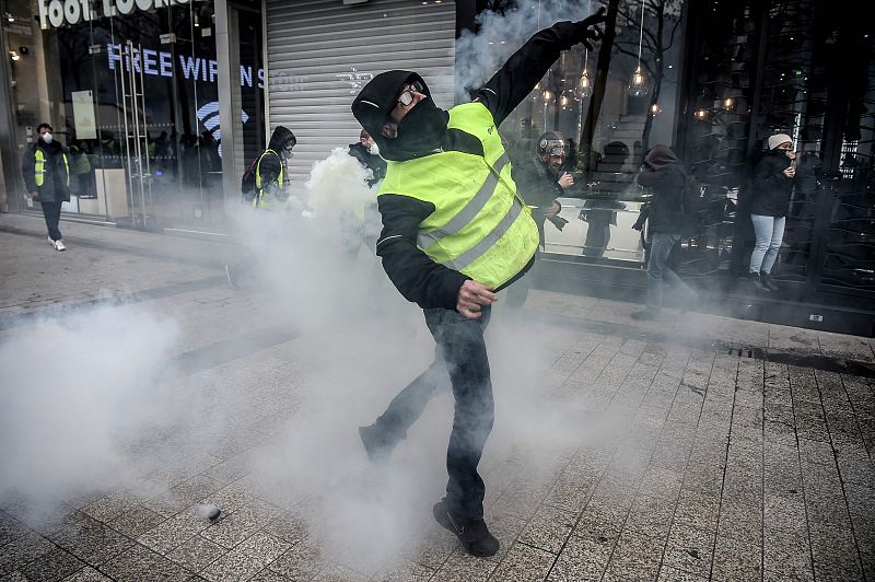 Un manifestante arroja un objeto a la policía, que responde con gases lacrimógenos