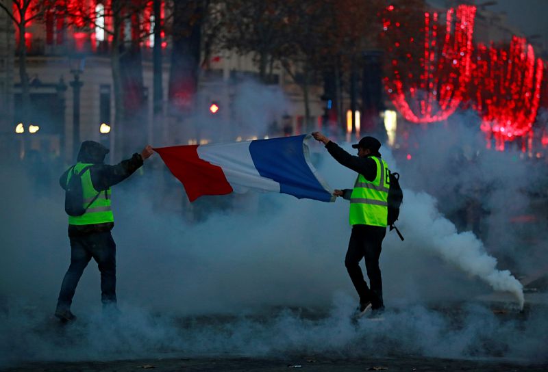 Dos manifestantes portan la bandera de Francia en los Campos Elíseos