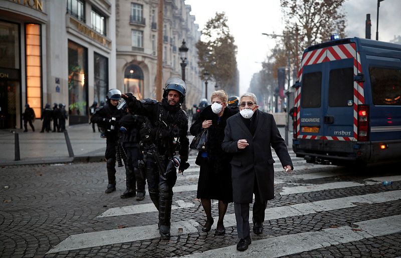 Un policía escolta a unos transeúntes mientras cruzan la calle