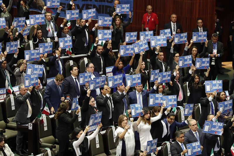 Legisladores mexicanos muestran carteles que rezan "Que baje la gasolina" durante la ceremonia de investidura de López Obrador