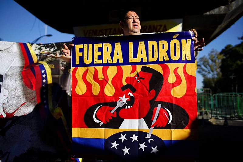 Un hombre con una pancarta que reza "Fuera ladrón" en referencia al presidente de Venezuela, Nicolás Maduro, en el exterior del Congreso