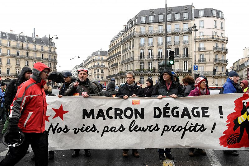 Los manifestantes portan una pancarta que reza "Macron vete; nuestras vidas, no sus beneficios"
