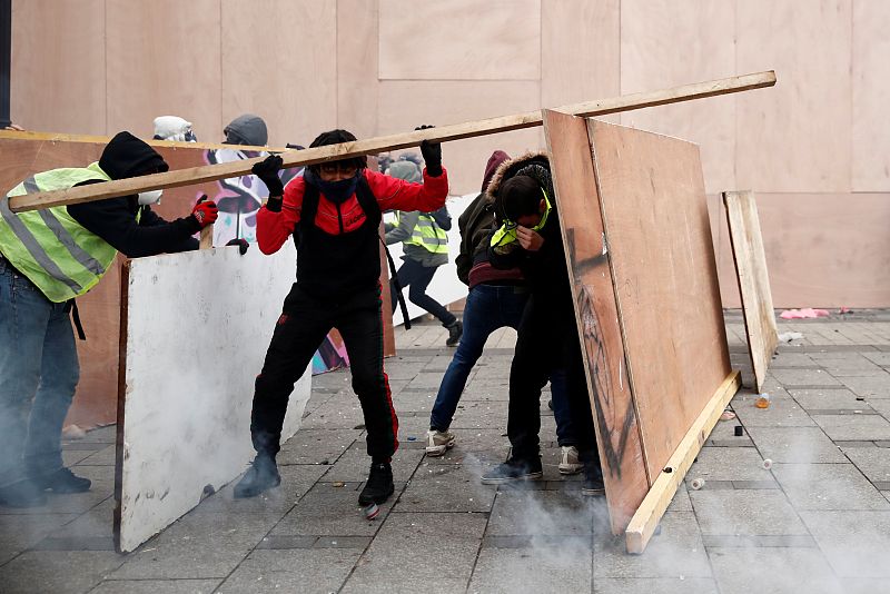 Un grupo de manifestantes se protege con láminas de madera