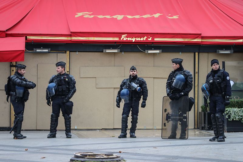 Agentes antidisturbios permanecen a la espera frente a un restaurante en los Campos Elíseos