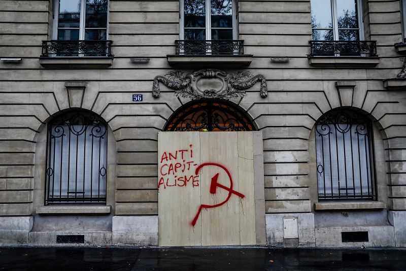 Un grafiti en contra del capitalismo escrito sobre una plancha de madera