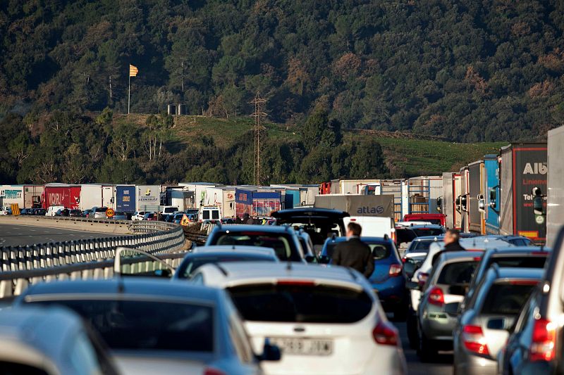 Decenas de vehículos permanecen atrapados durante la retención que ha provocado en la autopista AP-7 el corte que han realizado grupos independentistas que esperaban apostados en las cercanías de esta vía el momento propicio para proceder a su acción