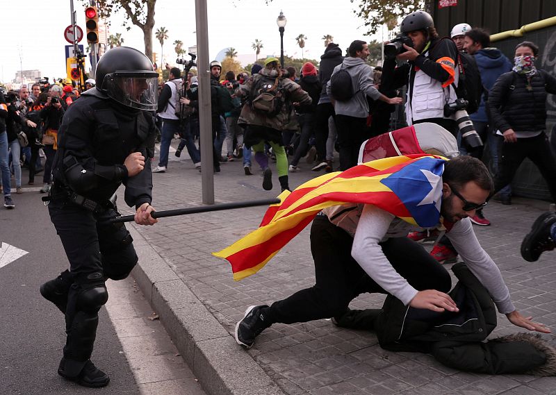 Un policía corre tras un manifestante durante la protesta en las inmediaciones de la Llotja de Mar de Barcelona, donde esta mañana se ha celebrado la reunión del Consejo de Ministros