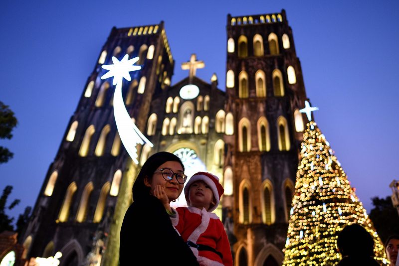 Una mujer vietnamita, con su hijo en brazos vestido de Papá Noel, en la catedral de St. Joseph.