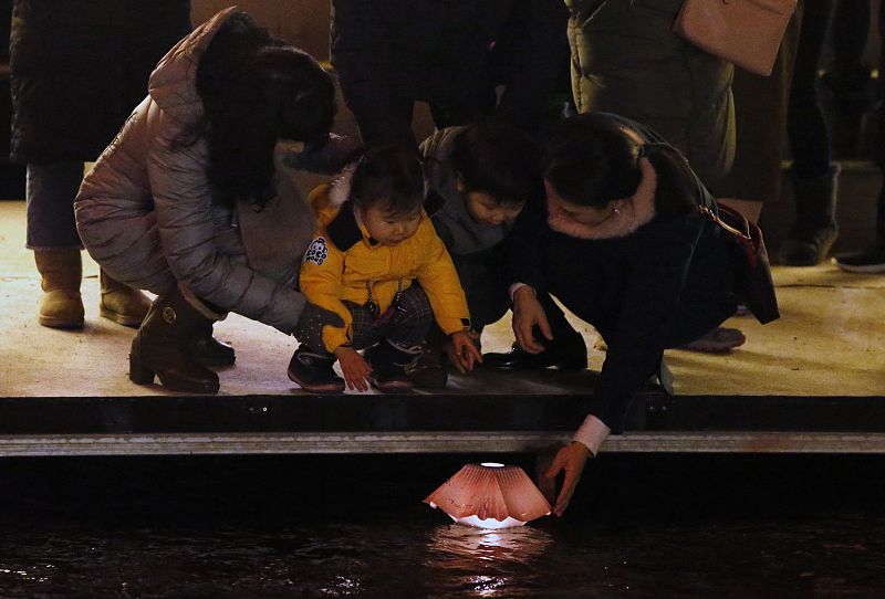 Una familia pone una lámpara flotante sobre el agua en la calle Cheonggye durante las celebraciones de Año Nuevo en Seúl, Corea del Sur.