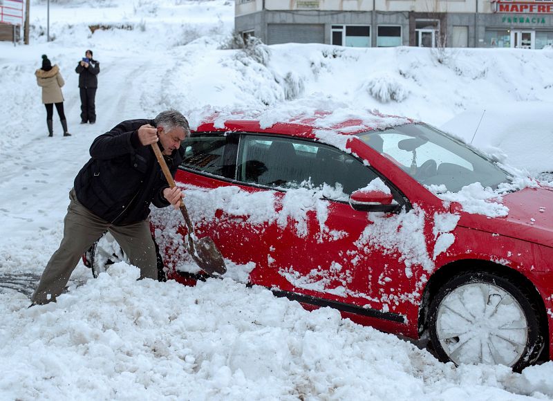 Un hombre intenta retirar su coche bloqueado por la nieve en Pedrafita do Cebreiro (Lugo).