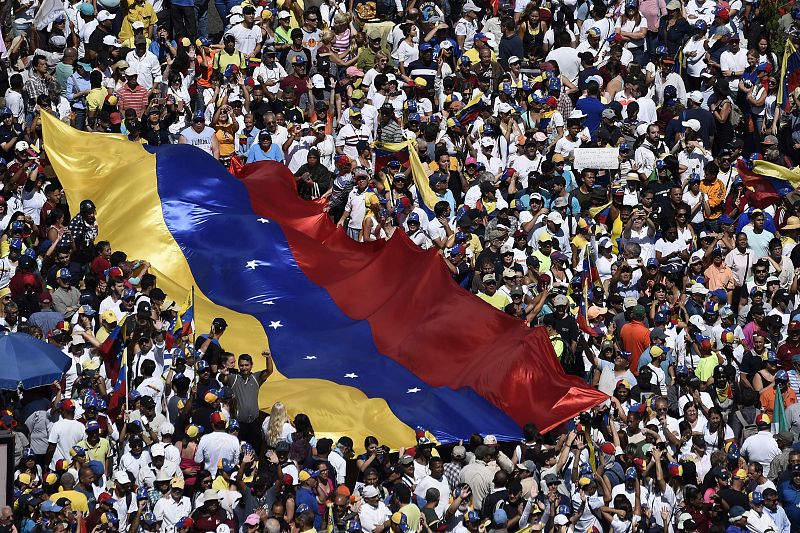 Opositores a Maduro se manifiestan en las calles de Caracas con una gran bandera de Venezuela