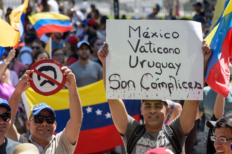 Manifestación convocada contra el presidente de Venezuela, Nicolás Maduro, en Santiago. En la imagen, un hombre con una pancarta en la que se lee "México, Vaticano y Uruguay son cómplices"