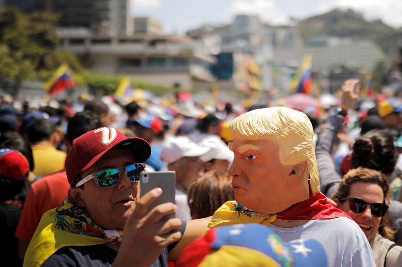 Un hombre con una máscara del presidente de EE.UU., Donald Trump, posa para un selfi durante la marcha convocada contra Maduro