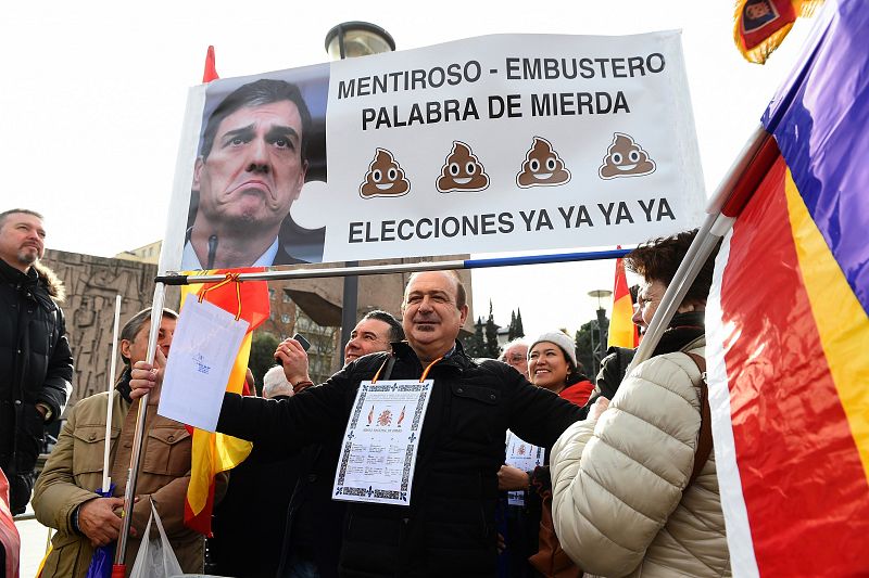 Un asistente a la manifestación en la plaza de Colón en Madrid con una pancarta en la que aparece una foto del presidente del Gobierno, Pedro Sánchez, junto a un texto que reza "Mentiroso-embustero"