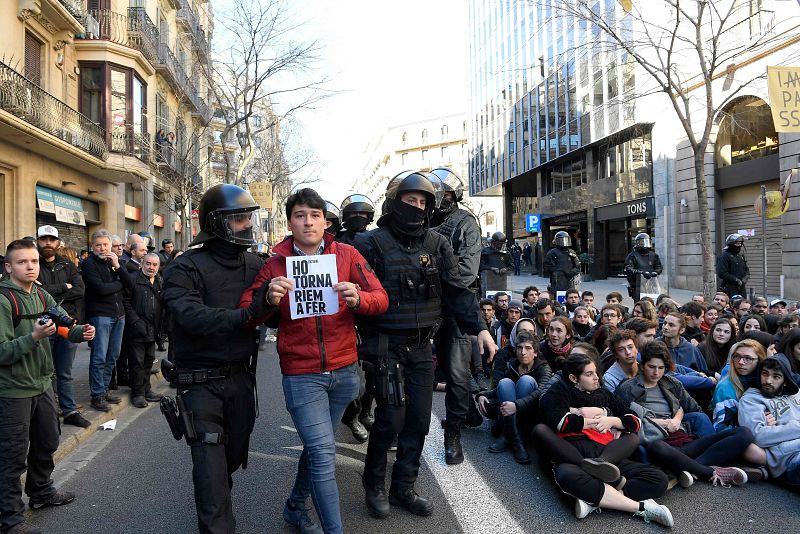 Los Mossos d'Esquadra desalojan a un hombre que porta un cartel que dice "Lo volveríamos a hacer de nuevo"