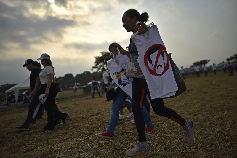 Varios asistentes al concierto Venezuela Aid Live sostienen camisetas con frases o ilustraciones contra el presidente del Gobierno, Nicolás Maduro.