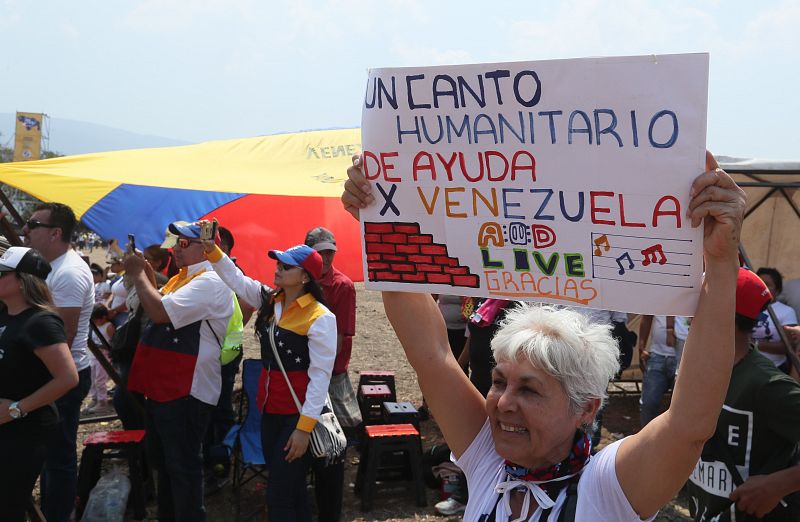 Una mujer sostiene un cartel que reza "Un canto humanitario de ayuda por Venezuela" durante el concierto 'Venezuela Aid Live'.