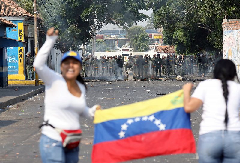 Dos manifestantes sujetan una bandera de Venezuela frente al dispositivo ordenado por Maduro para bloquear la entrada de ayuda humanitaria internacional desde Colombia.